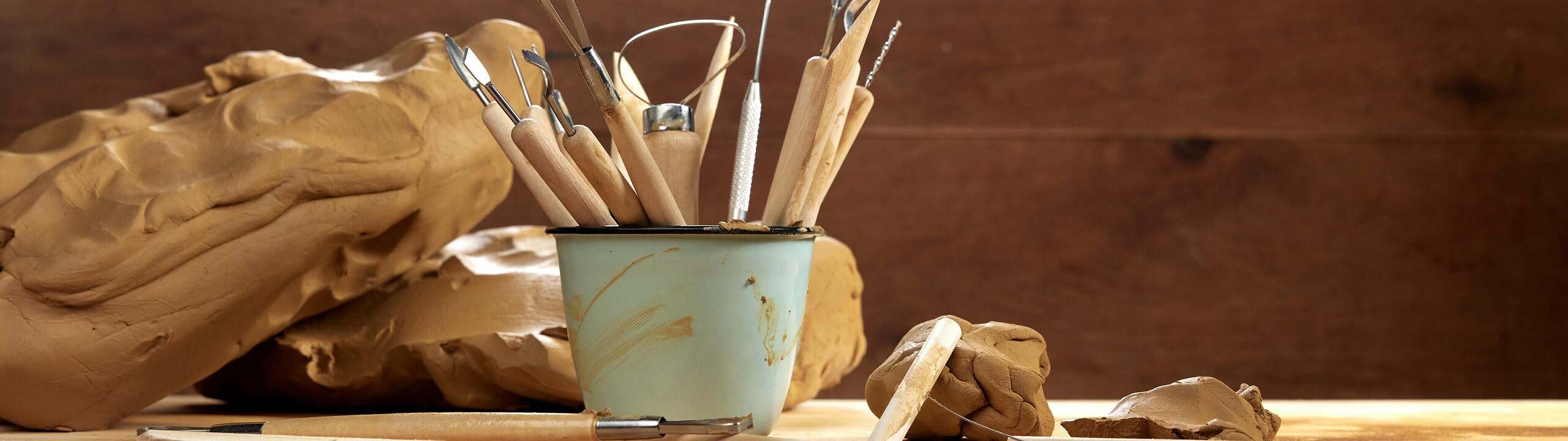 Töpferwerkzeug und roher Ton auf einer Werkbank